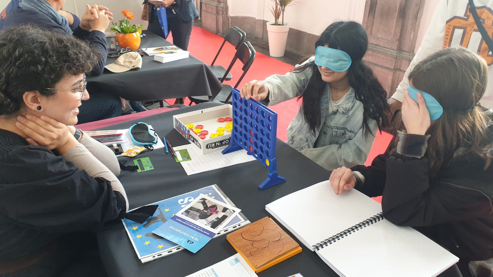 Two girls play the Connect Four game, while Soraya is watching over them