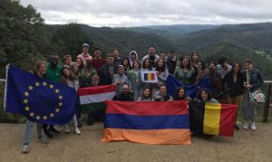 Participants posing in front of a landscape with national flags