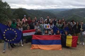Participants posing in front of a landscape with national flags