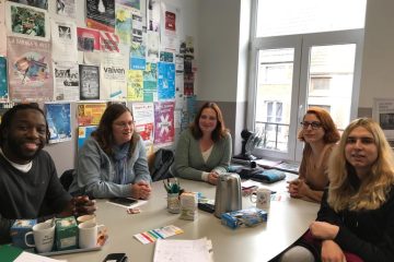 Patricia, her accompanying person Adriana and VI and La Baraka staff sitting around a table, smiling for the camera