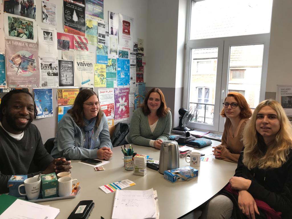 Patricia, her accompanying person Adriana and VI and La Baraka staff sitting around a table, smiling for the camera