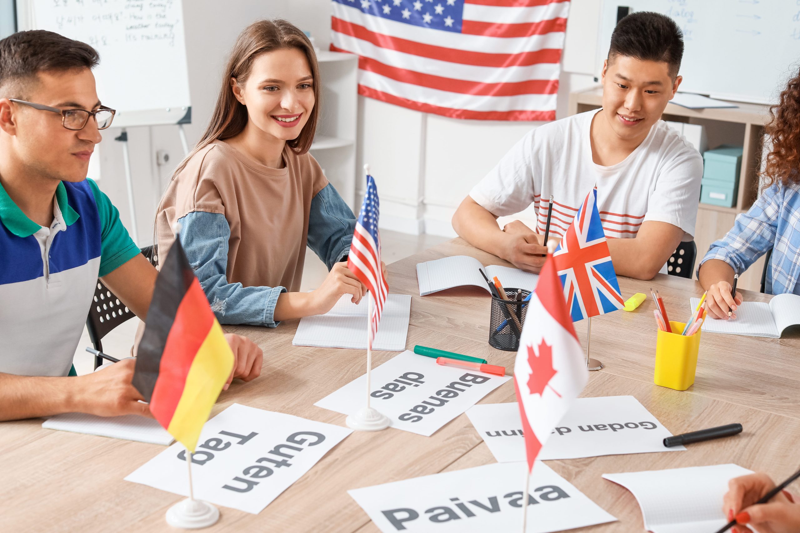 People around a table with flags and signs spelling "hello" in different languages