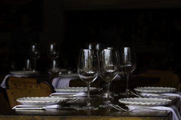 Dark dinner table with plates, wine glasses and cutlery