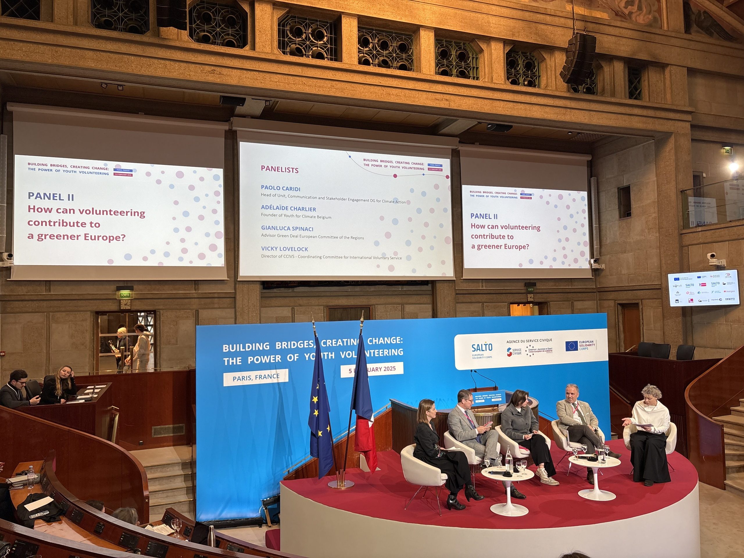 The stage with four panelists and a moderators sitting during the session "how can volunteering contribute to a greener Europe?" In the background, the screens with the title of the panel