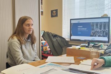 A picture of Lorie in VIEWS International's office, with documents in front of her.