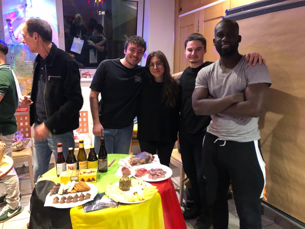 The belgian team behind a table with the belgian flag on intercultural night