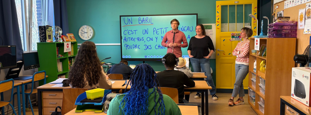 Jasper and two teachers are standing in front of a small class of students at IRHOV.
