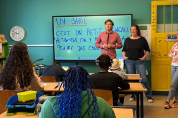 Jasper and two teachers are standing in front of a small class of students at IRHOV.