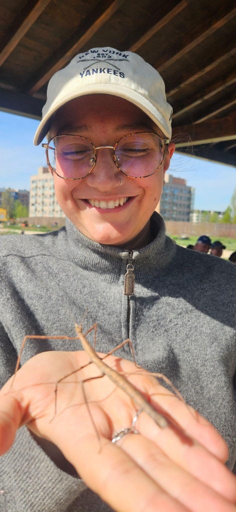 Louise with a stick insect on her hand while smiling.