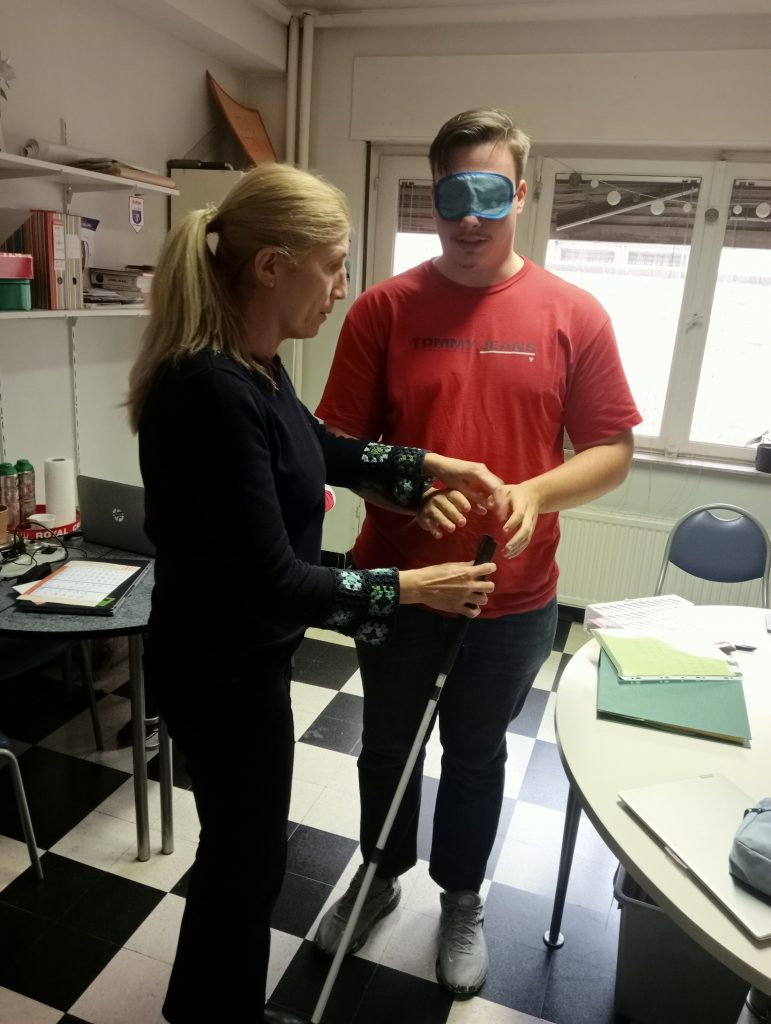 Silviu, blindfolded, learning how to use a white cane during his accessibility awareness session