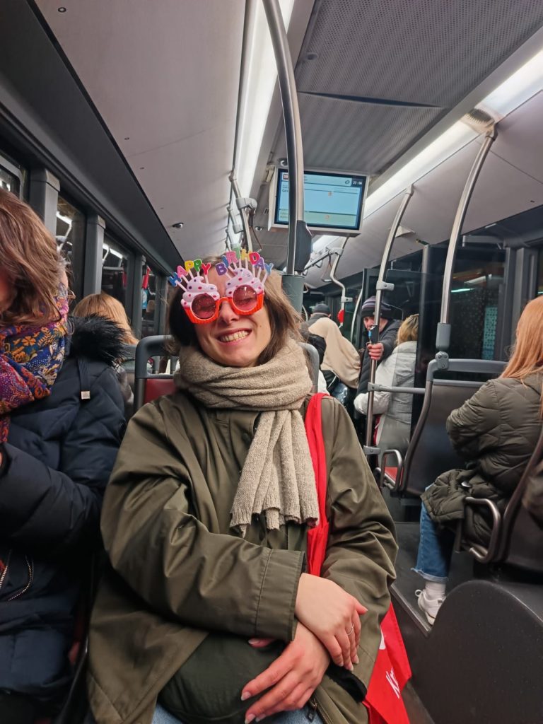 Sofia on a bus in Liège wearing sunglasses shaped like birthday cakes