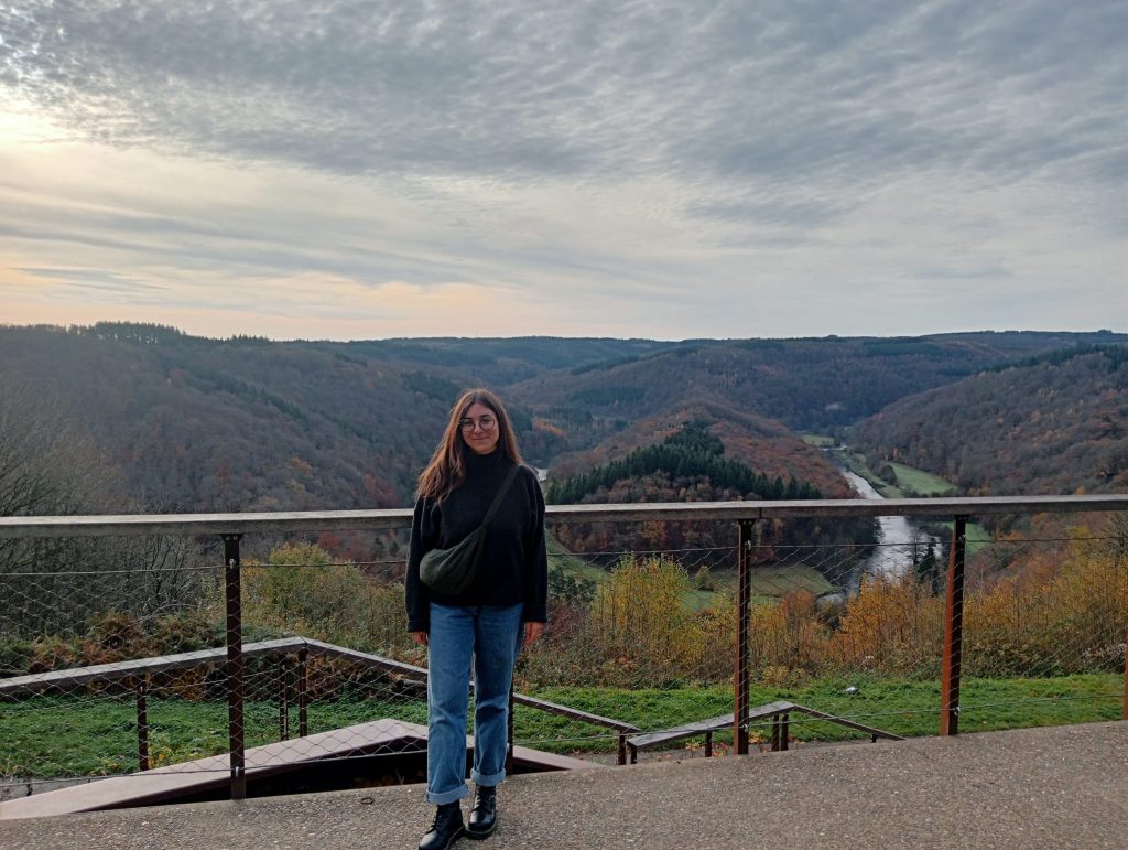Sofia posing in front of the Tombeau du Géant in Botassart. Behind her, a green landscape