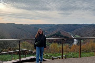 Sofia posing in front of the Tombeau du Géant in Botassart. Behind her, a green landscape
