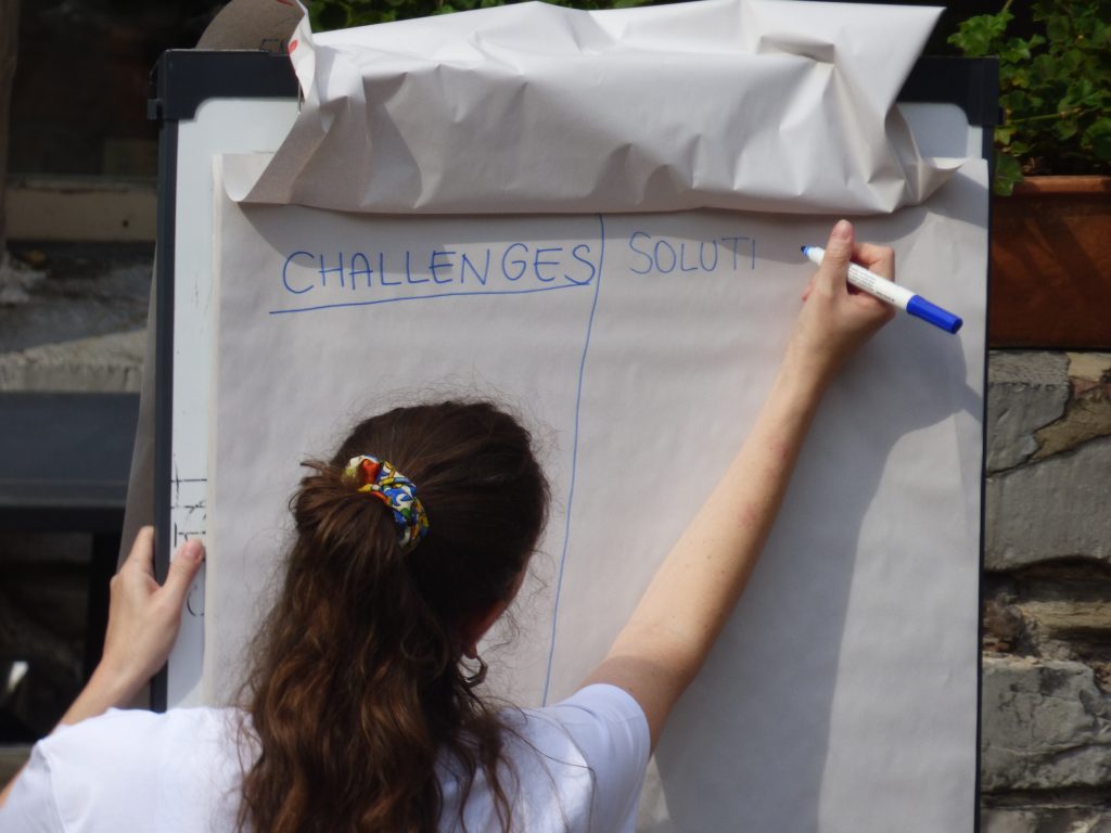Flipchart on which a facilitator is writing columns for challenges and solutions